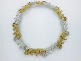 a close up of a gold and silver necklace on a white surface