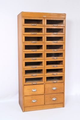 une armoire en bois comportant de nombreux tiroirs et surmontée de tiroirs