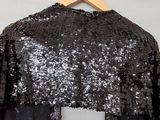 a black and silver sequinned top hanging on a wooden hanger