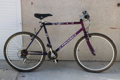 un vélo violet garé devant un garage