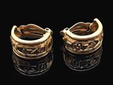 deux boucles d'oreilles en anneau dorées sur une surface noire, avec des reflets