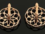 two pairs of gold earrings with black stones on a black surface