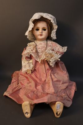 a doll that is sitting on the ground wearing a pink dress