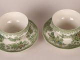 two green and white cups and saucers on a white surface