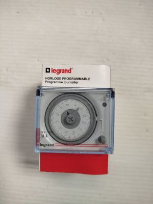 l'image d'une horloge posée sur une surface blanche, avec un socle rouge