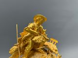 une statue en or représentant un homme à cheval, posée au sommet d'une autre statue