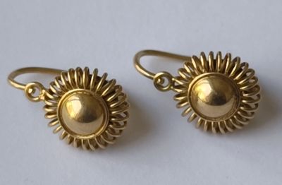 boucles d'oreilles plaquées or à motif « sunburst » sur un fond blanc