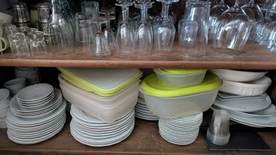 de nombreuses assiettes et verres sur une étagère dans la cuisine