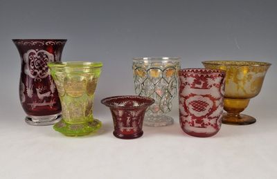 plusieurs vases en verre de différentes couleurs sont alignés sur une surface blanche