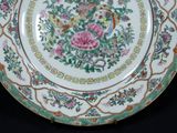 a plate with flowers and birds on it on a black surface