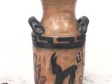 un vase marron orné d'un chat noir, posé sur une table