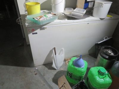 un réfrigérateur blanc et quelques bouteilles d'eau vertes posées par terre
