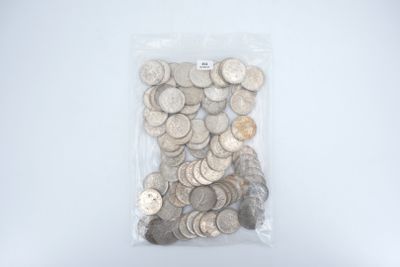 un sac rempli de pièces d'argent posé sur une surface blanche
