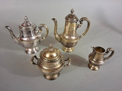 trois théières en argent et une cafetière sur une table