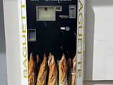 a vending machine that sells baguets outside of a building