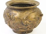 un vase en bronze orné d'un oiseau sur fond blanc