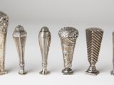 six silver spoons are lined up in a row on a white surface
