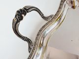 an antique silver plate with a curved handle and a curved handle