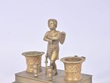 brass figurine of a boy with three cups on a stand