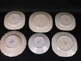 six white plates with different designs on them on a black surface