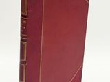 an old red book with gold trim on a white background