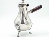 une cafetière ancienne en argent avec une poignée en bois sur un support