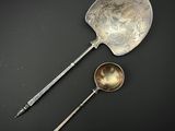 deux cuillères et un repose-cuillère posés sur une surface noire