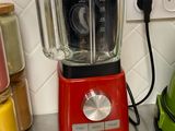 un mixeur rouge posé sur le plan de travail de la cuisine, à côté d'un mixeur vert