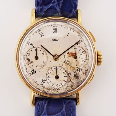 une montre en or avec des chiffres romains, montée sur un bracelet bleu