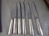 six silverware knives and a knife rest on a table next to a knife