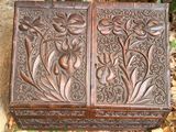 carved wooden box sitting on top of a pile of leaves