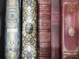 several old books are lined up in a row on a shelf