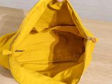 someone is holding a yellow purse on a wooden table