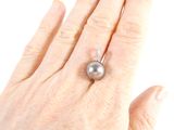 a woman ' s hand holding a ring with a pearl on it