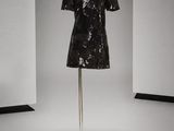 une robe noire à paillettes posée sur un mannequin dans une pièce blanche