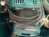 a green box filled with tools like a corded sander and a drill