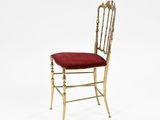 a gold metal chair with a red cushion on top of it