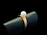 a close up of a ring with a pearl on top of it