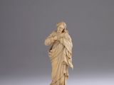 une figurine en ivoire représentant une femme tenant un enfant dans ses bras, posée sur un socle en bois
