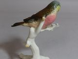 a small figurine of a bird sitting on a branch