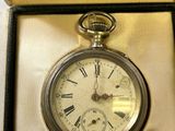 a silver pocket watch inside of a box on a table