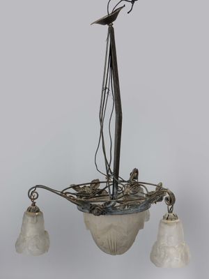 chandelier with three glass shades and a bird on top of it