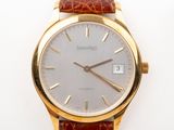 a gold wrist watch with a brown leather strap