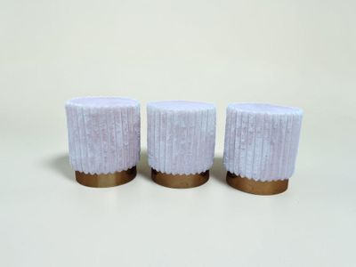 trois bougies blanches bordées d'or, posées sur une surface blanche
