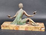 bronze statue of a woman sitting on a marble base holding two birds