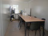 a long table and chairs in a room with a refrigerator