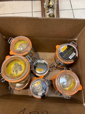 de nombreux bocaux de conserve dans un carton posé par terre