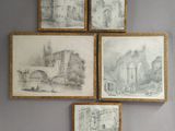four framed drawings of a castle on a wall above a bed