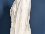 a white jacket on a mannequin stand against a blue wall