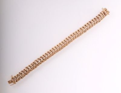 gros plan d'un bracelet en or sur une surface blanche